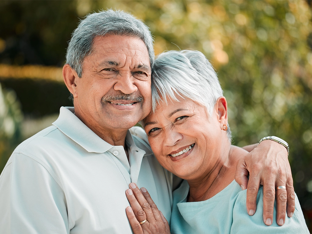 Loving older couple hugging and smiling together outdoors